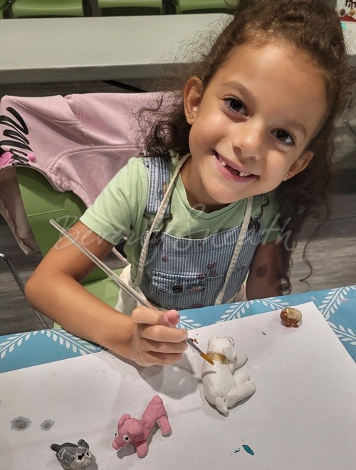 Little girl painting clay sculptures